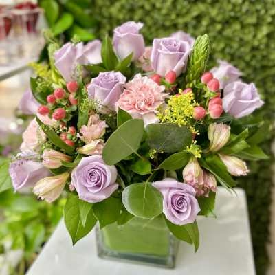 Lavender roses and pink carnations with berries in a square glass vase