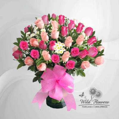 Bouquet of pink and peach roses in a vase with a pink ribbon