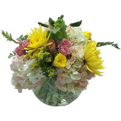 Bouquet of yellow daisies, pink roses, and pale hydrangeas in a glass vase