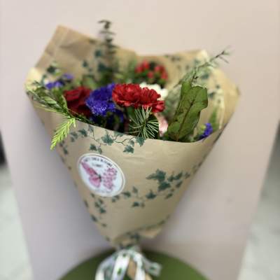 Wrapped bouquet of red and purple flowers with greenery