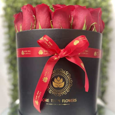 Round black hatbox filled with red roses and tied with a red ribbon bow