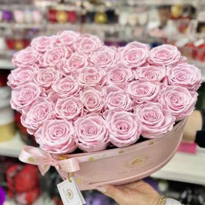 Heart-shaped arrangement of light pink roses in a pink hat box with ribbon.