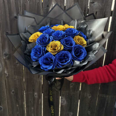 Bouquet of blue and gold roses wrapped in black paper