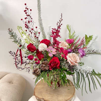 Tall mixed floral arrangement in a glass vase with red, pink, and white blooms