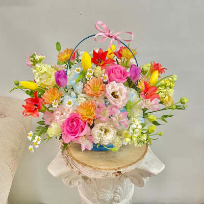Colorful mixed flower basket with a pink ribbon handle