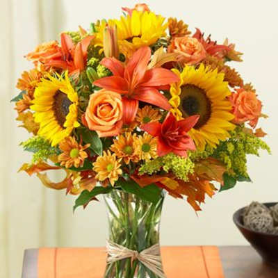 Bouquet of sunflowers, roses, lilies, and daisies in a glass vase