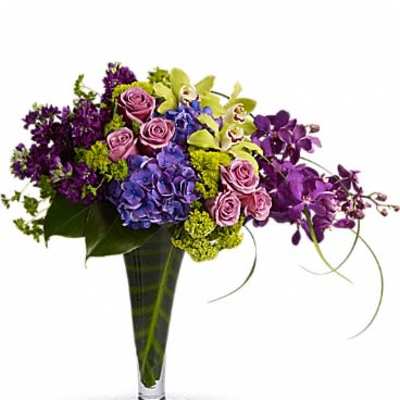 Purple and pink floral arrangement in a tall glass vase