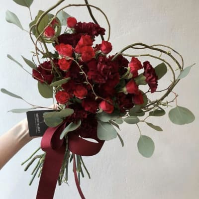 Red roses and dark red carnations in a hand-tied bouquet with ribbon