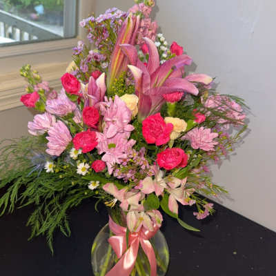 Pink and lavender mixed bouquet in a glass vase with a ribbon