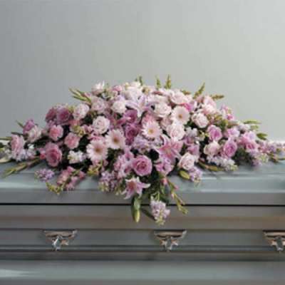 Pink and white floral casket spray on a gray casket
