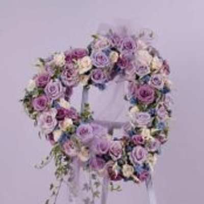 Lavender and white floral wreath on a stand with trailing greenery
