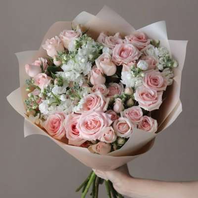 Bouquet of pale pink roses and white flowers wrapped in blush paper