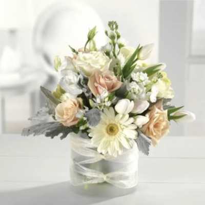 Bouquet of white and blush flowers in a clear vase with a ribbon
