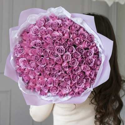 Large bouquet of pink roses wrapped in lavender paper