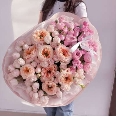 Large bouquet of pink and peach roses wrapped in pale pink paper