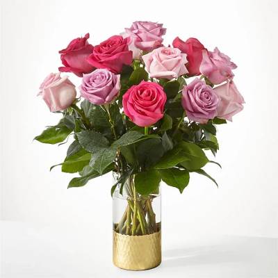 Arrangement of pink and lavender roses in a clear vase with a gold metal base