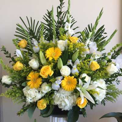 Yellow and white floral arrangement with roses, lilies, and daisies