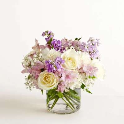 Low glass vase arrangement with cream roses, white blooms, and soft pink and lavender flowers