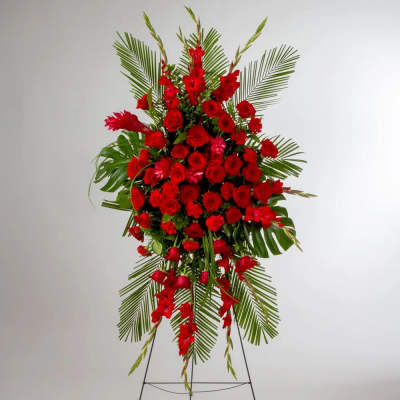 Tall standing spray of red flowers on a metal easel with large palm fronds.