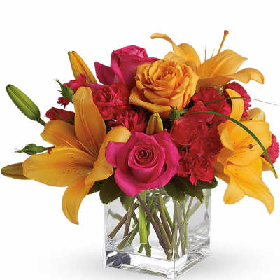 Pink and yellow flowers arranged in a clear glass vase
