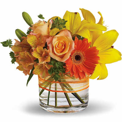 Bouquet of yellow lilies, peach roses, and orange gerbera daisies in a glass vase