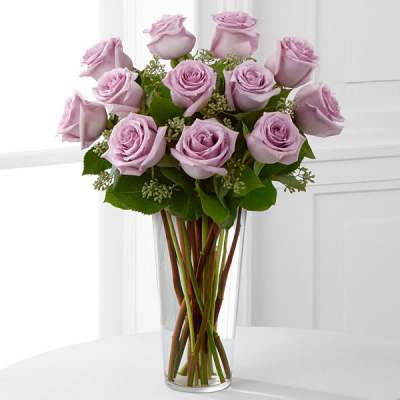Tall arrangement of light lavender roses in a clear glass vase