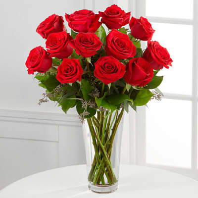 Tall arrangement of long-stem red roses in a clear glass vase