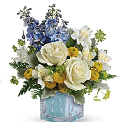 White roses and blue flowers in a blue cube vase