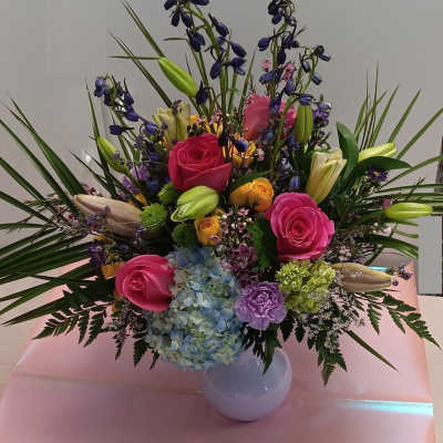 Colorful mixed bouquet in a white vase with roses, lilies, and hydrangea