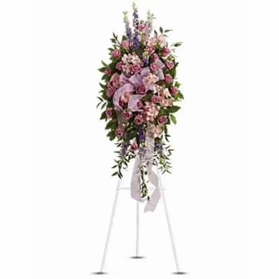 Standing floral spray with pink roses and purple flowers on a white easel