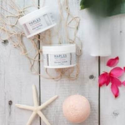 Spa products with a starfish and pink flower petals on a white wood background