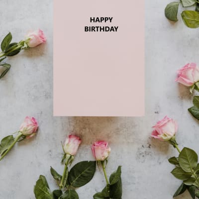 Pink roses arranged around a card that says Happy Birthday