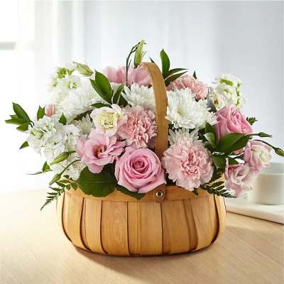Pastel pink roses, carnations, and white mums arranged in a wooden handled basket