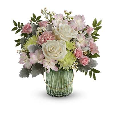 Pastel arrangement of cream roses, pink blooms, and green mums in a green glass vase