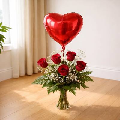 Red roses in a glass vase with a heart-shaped balloon