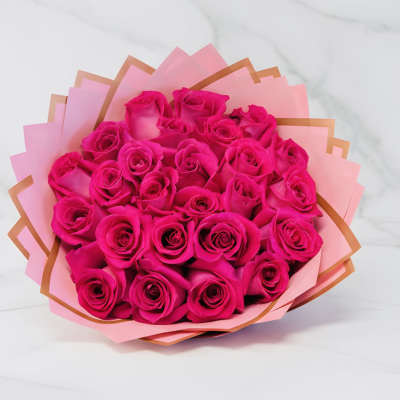 Bouquet of bright hot pink roses wrapped in layered pink and peach paper