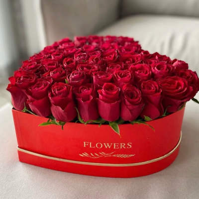 Heart-shaped box of red roses on a light surface