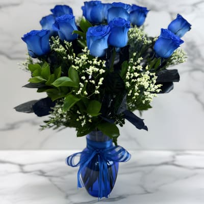 Blue roses in a glass vase with a blue ribbon