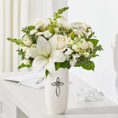 White floral arrangement in a tall vase with a cross emblem