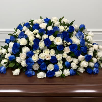 Large arrangement of blue and white roses on a wooden casket