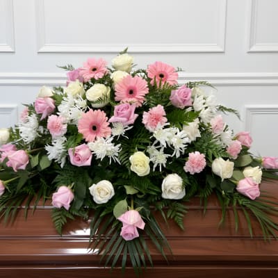 Pink and white floral casket spray with roses and daisies