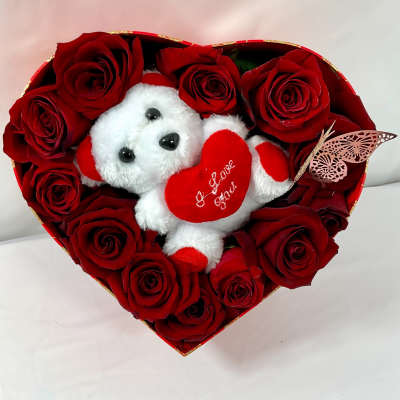 Heart-shaped box of red roses with a small teddy bear holding a heart
