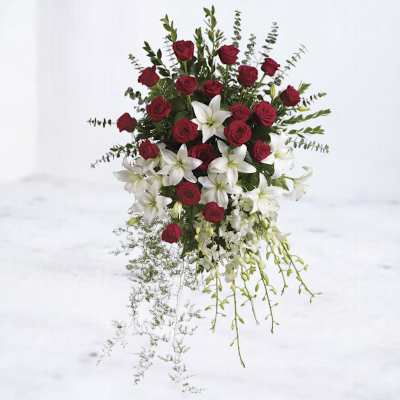 Standing arrangement of red roses and white lilies with trailing greenery