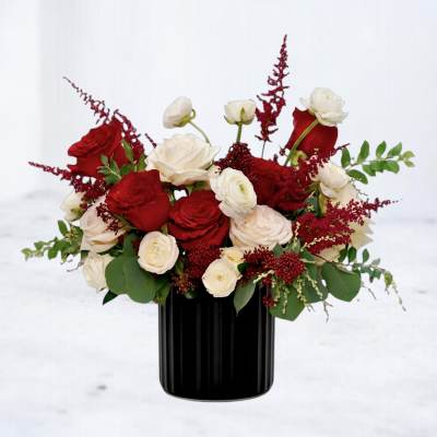 Red and white rose arrangement in a black vase