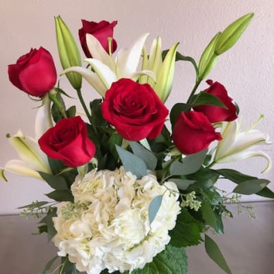 Bouquet of red roses and white lilies with white hydrangea in a glass vase