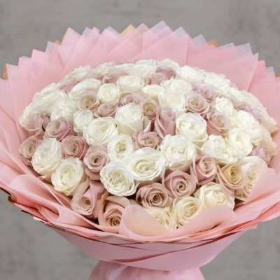 Bouquet of pale pink and white roses wrapped in pink paper