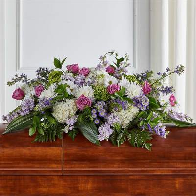 Casket spray with pink roses, white blooms, and purple flowers
