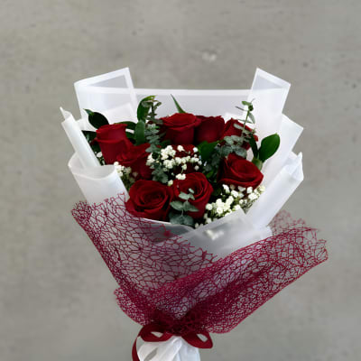 Bouquet of red roses wrapped in white and burgundy paper