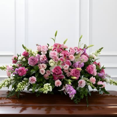Large pink and white floral casket spray on a polished coffin