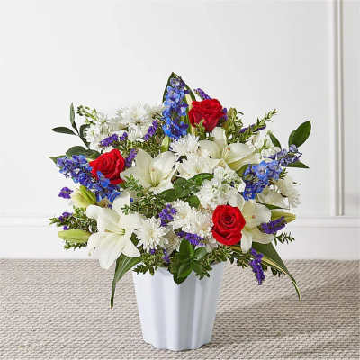 Bouquet of red roses, white lilies, and purple flowers in a white vase